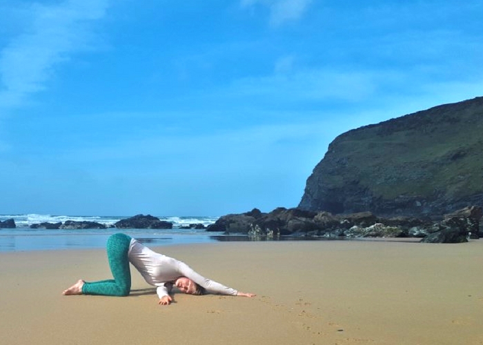 thread the needle yoga pose on beach cliffs and sea cornwall