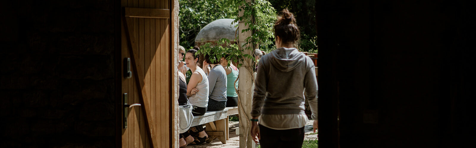 person walking out door to people seated outside - hiking yoga holiday montenegro