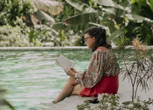 lady reading book with feet in pool