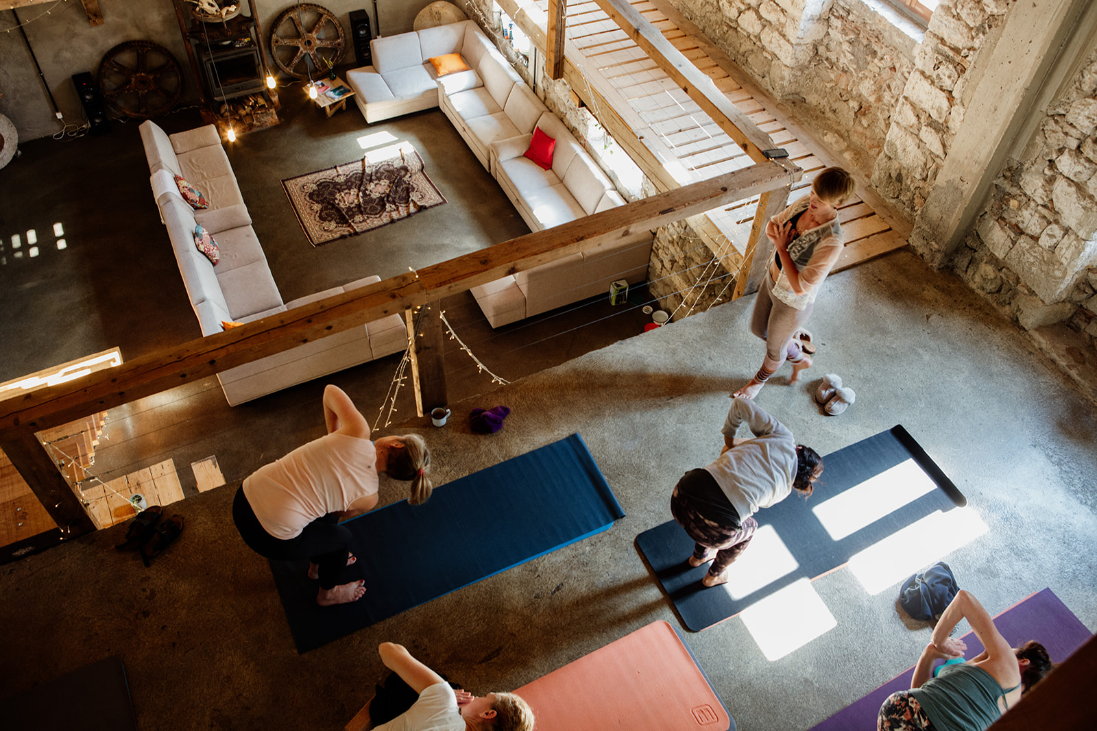aerial image yoga teacher walking and people doing side twist in prayer on mats - hiking yoga holiday montenegro