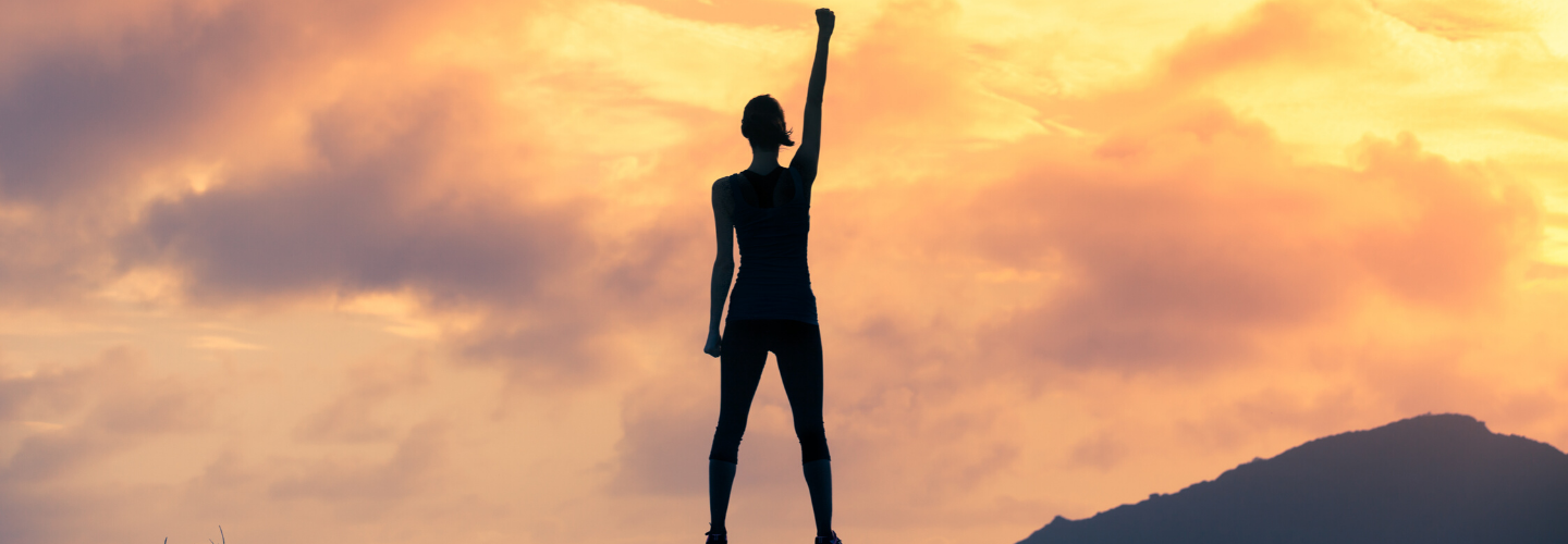 woman standing fist in air sunset