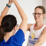 yoga teacher natasha lincoln helping student with pose