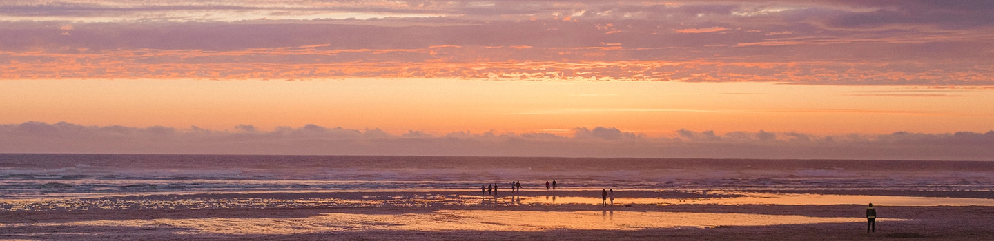 people on the beach in cornwall at sunset on new year yoga retreats