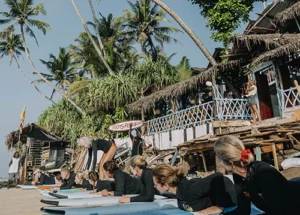 people lying on surf boards in sri lanka having a surf lesson on a yoga retreat