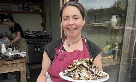grace frain vegan chef smiling to camera with vegan dish